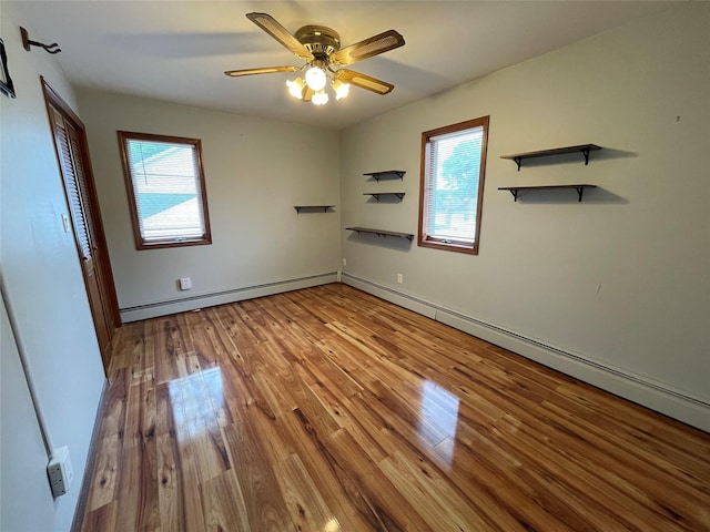 74 Webster Ave, West Islip, NY 11795 - unfurnished bedroom featuring multiple windows, wood finished floors, a baseboard heating unit, and a ceiling fan