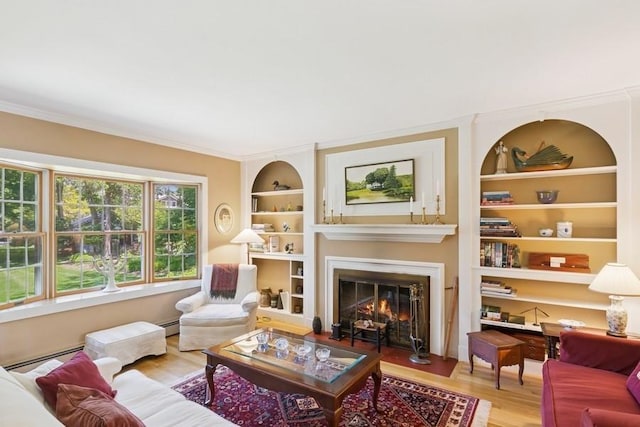 43 Hill St, Wading River, NY 11792 - living area with wood finished floors, a glass covered fireplace, built in shelves, ornamental molding, and baseboard heating