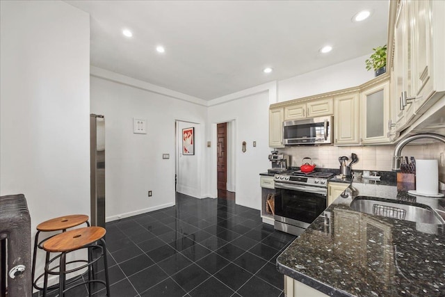27 Locust Ave Unit 4N, New Rochelle, NY 10801 - kitchen with appliances with stainless steel finishes, cream cabinetry, a sink, decorative backsplash, and glass insert cabinets