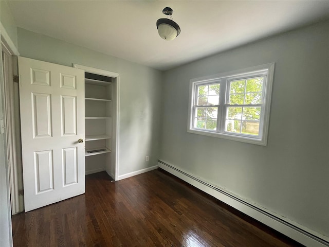 10 Kirby Ln, Central Islip, NY 11722 - unfurnished bedroom with a baseboard heating unit, dark wood-type flooring, and baseboards