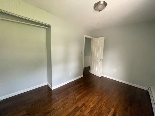 10 Kirby Ln, Central Islip, NY 11722 - unfurnished bedroom featuring a baseboard heating unit, dark wood finished floors, and baseboards