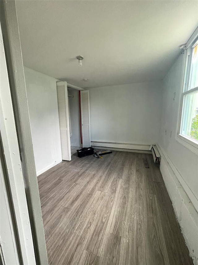 10 Kirby Ln, Central Islip, NY 11722 - empty room with baseboard heating, wood finished floors, and baseboards