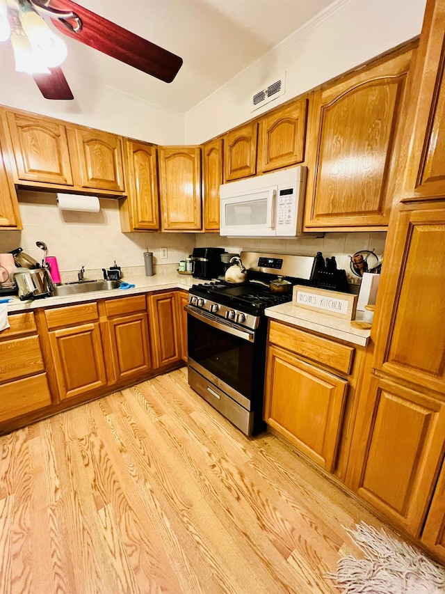5-41 117th St, College Point, NY 11356 - kitchen featuring white microwave, stainless steel range with gas stovetop, light wood finished floors, and brown cabinetry