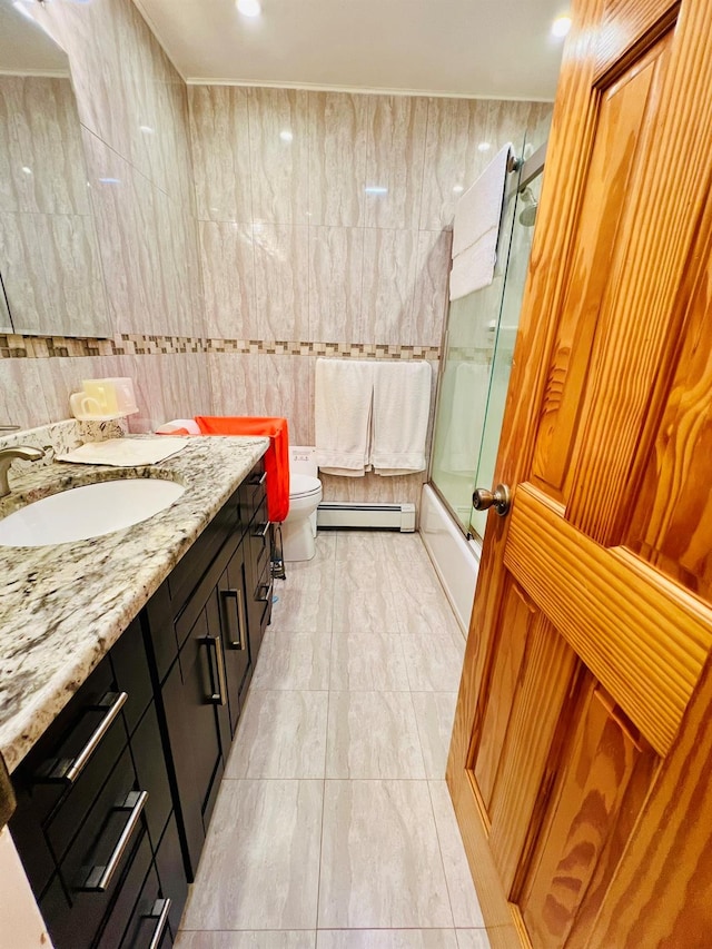5-41 117th St, College Point, NY 11356 - full bath featuring a baseboard heating unit, vanity, bath / shower combo with glass door, toilet, and tile walls