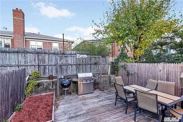 5-41 117th St, College Point, NY 11356 - wooden deck with outdoor dining area, grilling area, and a fenced backyard