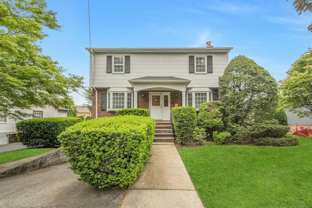 115 Fowler Ave, Yonkers, NY 10701 - traditional-style house with brick siding, a front yard, and a chimney