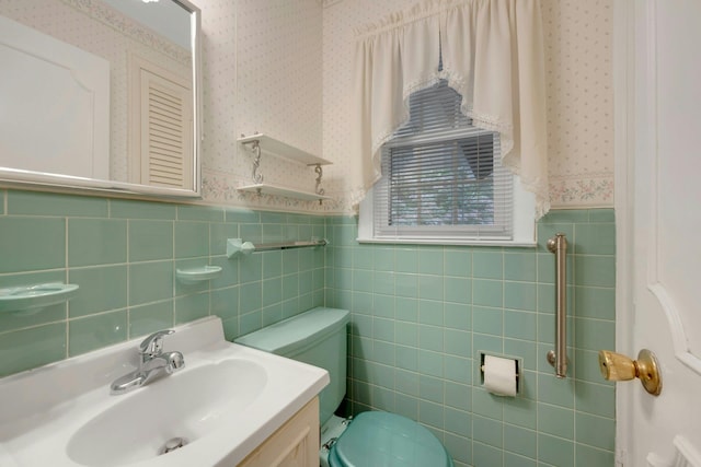 115 Fowler Ave, Yonkers, NY 10701 - bathroom with wallpapered walls, wainscoting, toilet, vanity, and tile walls