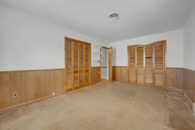 115 Fowler Ave, Yonkers, NY 10701 - unfurnished bedroom with a wainscoted wall, wooden walls, carpet floors, and multiple closets