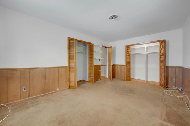 115 Fowler Ave, Yonkers, NY 10701 - unfurnished bedroom featuring a wainscoted wall, wooden walls, carpet floors, and multiple closets
