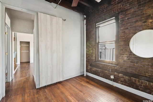 21-16 35th St Unit 5B, Astoria, NY 11105 - spare room with dark wood-style flooring, baseboards, and brick wall