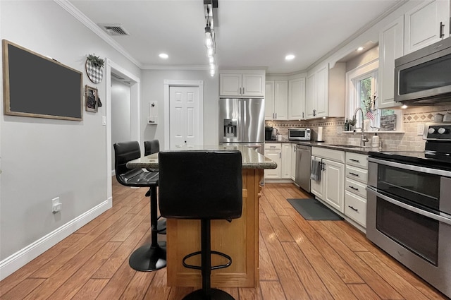 20 Shale Dr, Wappingers Falls, NY 12590 - kitchen featuring stainless steel appliances, a center island, a sink, ornamental molding, and white cabinetry