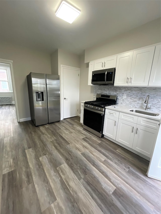 32 Moquette Row S, Yonkers, NY 10703 - kitchen with stainless steel appliances, a sink, radiator heating unit, tasteful backsplash, and white cabinetry
