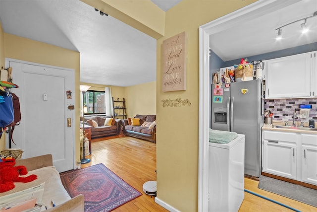 35 Lawrence Dr Unit A, White Plains, NY 10603 - kitchen with stainless steel refrigerator with ice dispenser, white cabinets, a sink, light wood-style flooring, and tasteful backsplash