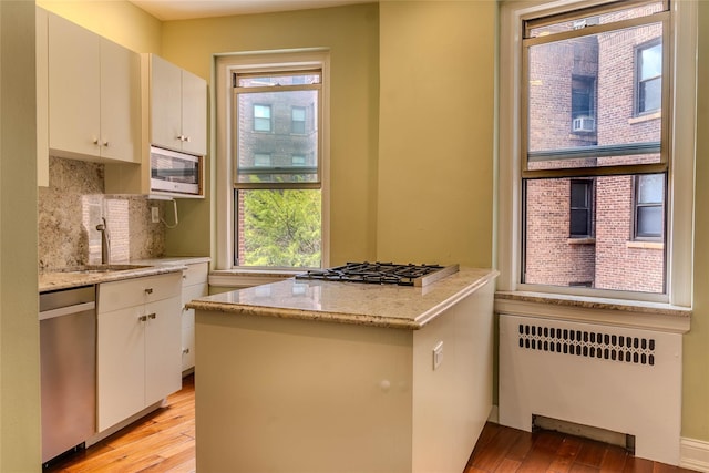 8 Barstow Rd Unit 4F, Great Neck, NY 11021 - kitchen with radiator, appliances with stainless steel finishes, light wood-style floors, a peninsula, and plenty of natural light