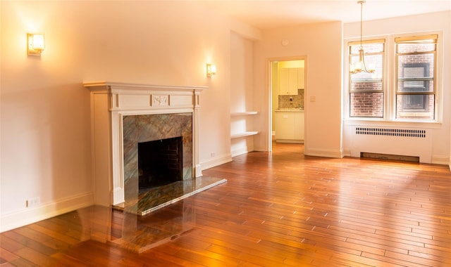 8 Barstow Rd Unit 4F, Great Neck, NY 11021 - unfurnished living room with radiator, wood-type flooring, a premium fireplace, and baseboards