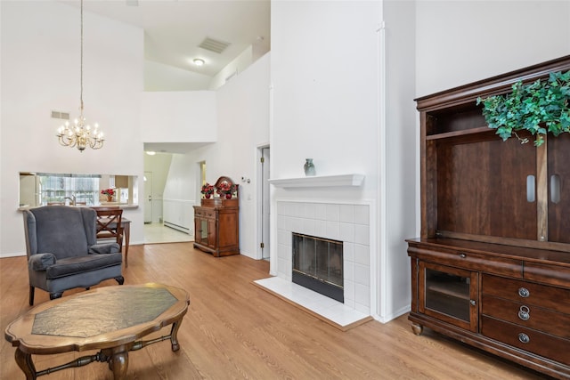 30 Joyces Way, Bay Shore, NY 11706 - living area featuring a chandelier, light wood-style flooring, a tiled fireplace, a baseboard radiator, and lofted ceiling