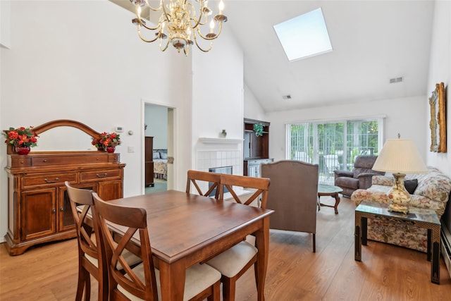 30 Joyces Way, Bay Shore, NY 11706 - dining area featuring high vaulted ceiling, a skylight, a chandelier, a tiled fireplace, and light wood-style flooring