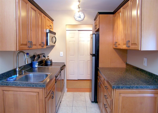 263 River Ave Unit 52, Patchogue, NY 11772 - kitchen featuring stainless steel appliances, a sink, dark countertops, light tile patterned floors, and brown cabinets