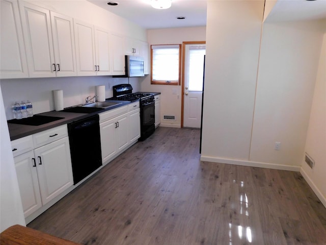 7 Audrey Ln, Commack, NY 11725 - kitchen featuring black appliances, dark countertops, white cabinets, a sink, and wood finished floors
