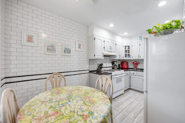 64-30 73rd Pl, Middle Village, NY 11379 - kitchen with white appliances, under cabinet range hood, white cabinetry, dark countertops, and recessed lighting