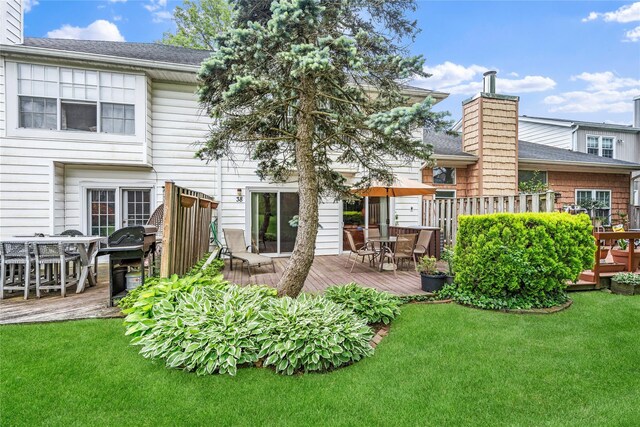 38 The Mews, Syosset, NY 11791 - back of property with a chimney, roof with shingles, a wooden deck, and outdoor dining area