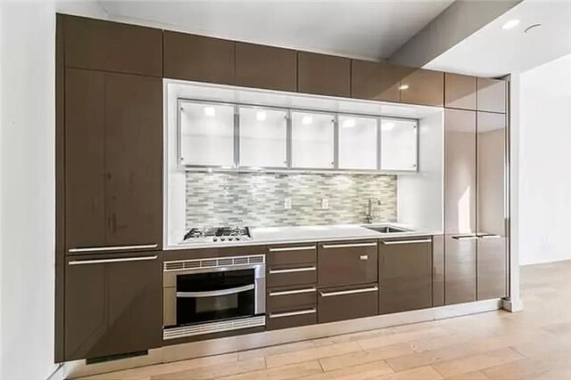 75 Wall St Unit 26J, New York Manhattan, NY 10005 - indoor wet bar featuring wall oven, decorative backsplash, and stainless steel gas stovetop