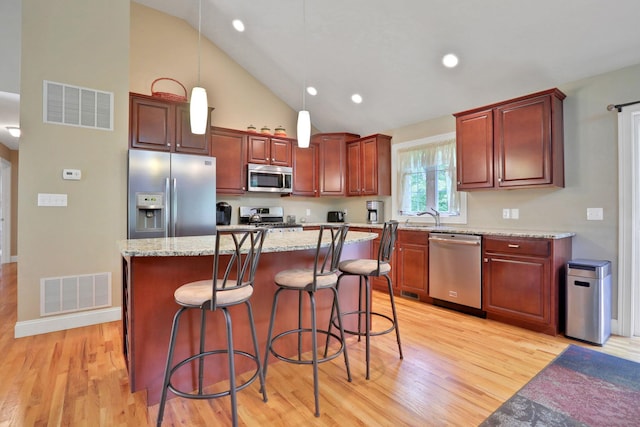 390 Lakeside Rd, Newburgh, NY 12550 - kitchen featuring stainless steel appliances, light wood finished floors, decorative light fixtures, a breakfast bar, and high vaulted ceiling