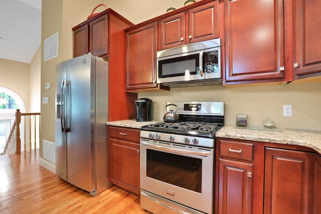 390 Lakeside Rd, Newburgh, NY 12550 - kitchen with stainless steel appliances, light wood-type flooring, reddish brown cabinets, and light stone countertops