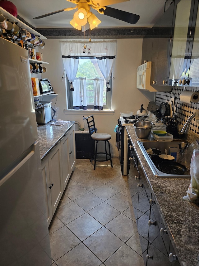 86-70 Francis Lewis Unit A55, Holliswood, NY 11427 - kitchen with freestanding refrigerator, white microwave, range, light tile patterned floors, and a ceiling fan
