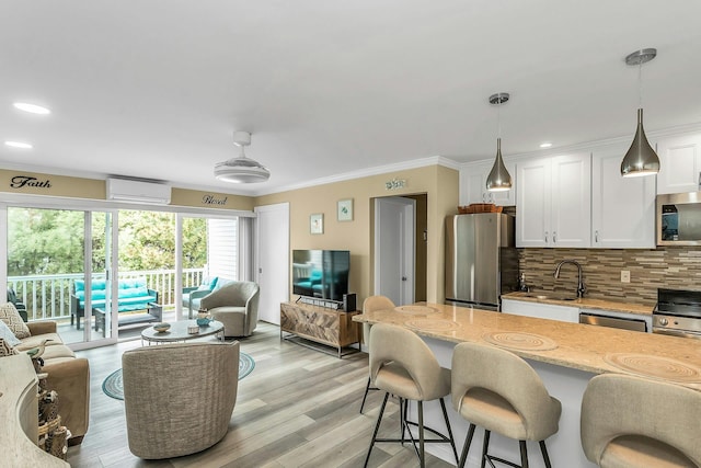 281 Dune Rd Unit 18A, Westhampton Beach, NY 11978 - kitchen with appliances with stainless steel finishes, an AC wall unit, ornamental molding, white cabinetry, and light stone counters
