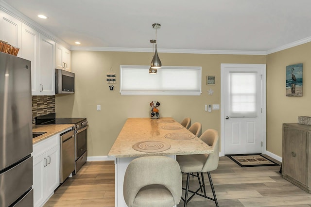 281 Dune Rd Unit 18A, Westhampton Beach, NY 11978 - kitchen with appliances with stainless steel finishes, a breakfast bar, white cabinetry, crown molding, and light wood-style floors