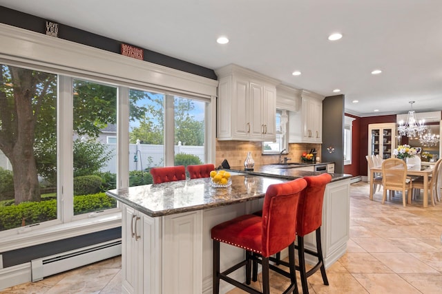 6 W Shore Rd, Bay Shore, NY 11706 - kitchen with a baseboard heating unit, a sink, backsplash, dark stone counters, and recessed lighting