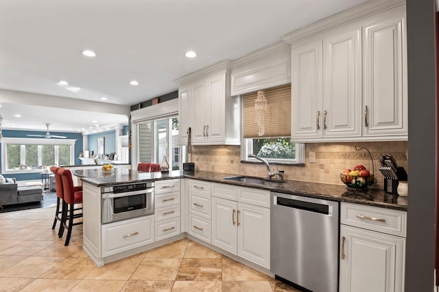 6 W Shore Rd, Bay Shore, NY 11706 - kitchen featuring appliances with stainless steel finishes, a peninsula, open floor plan, white cabinetry, and decorative backsplash