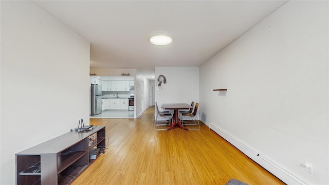 37-40 61st St, Woodside, NY 11377 - living area featuring a baseboard heating unit and light wood-style floors
