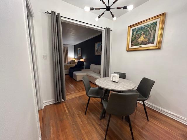 86-10 34th Ave Unit 624, Jackson Heights, NY 11372 - dining space featuring a chandelier, wood finished floors, and baseboards