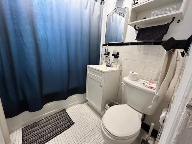 86-10 34th Ave Unit 624, Jackson Heights, NY 11372 - full bath featuring toilet, vanity, shower / tub combo with curtain, tile walls, and tile patterned flooring