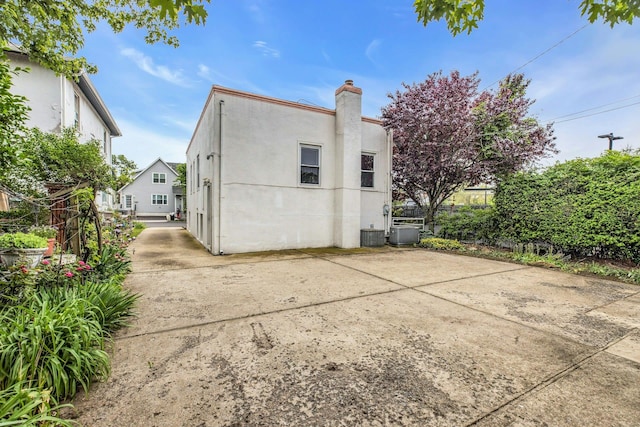 5 E Walnut St, Long Beach, NY 11561 - rear view of property featuring a chimney, stucco siding, a patio, and central AC unit