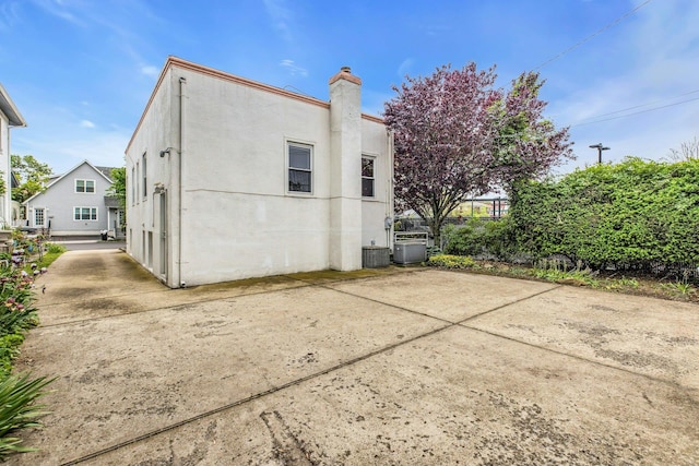 5 E Walnut St, Long Beach, NY 11561 - back of property featuring a chimney, stucco siding, central AC, and a patio area