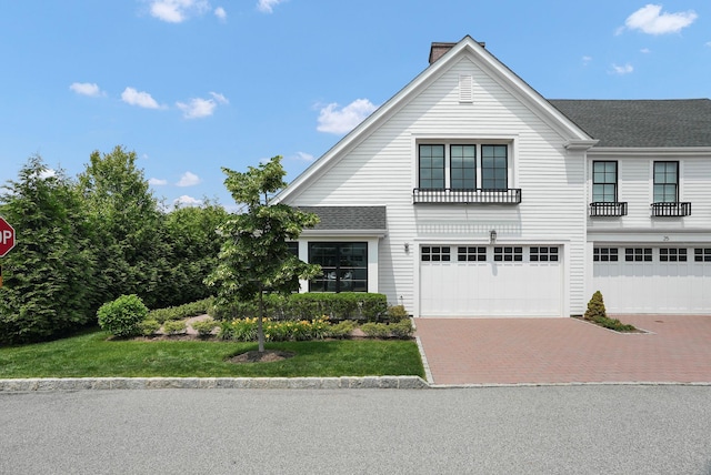 27 Lavender Ln, Rye Brook, NY 10573 - view of front facade featuring decorative driveway, a garage, a chimney, and roof with shingles