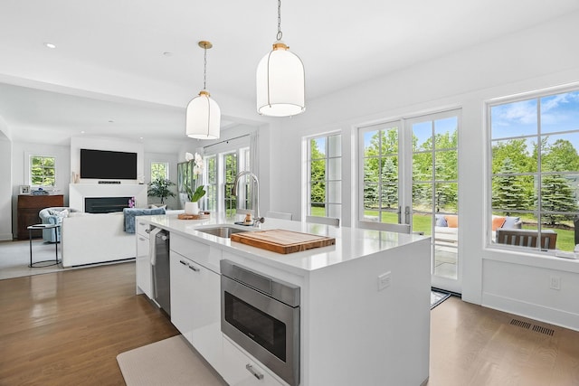27 Lavender Ln, Rye Brook, NY 10573 - kitchen featuring appliances with stainless steel finishes, wood finished floors, a fireplace, light countertops, and recessed lighting