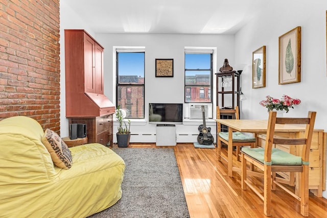 161 W 133rd St, New York Manhattan, NY 10030 - living room with light wood finished floors, cooling unit, a baseboard heating unit, and brick wall