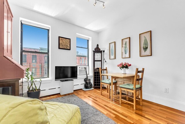 161 W 133rd St, New York Manhattan, NY 10030 - living area with a baseboard heating unit, light wood-style floors, and baseboards