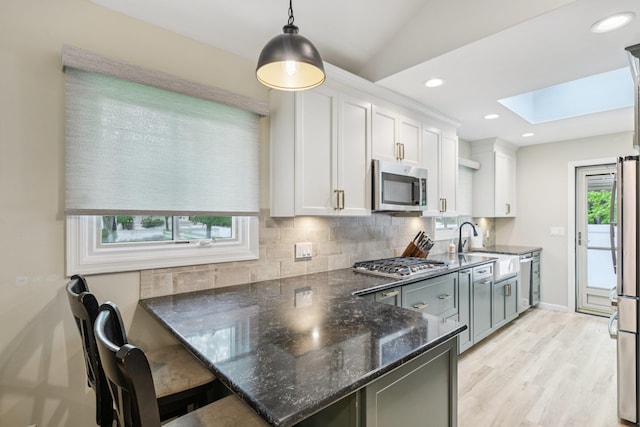 422 Old Bridge Rd, Northport, NY 11768 - kitchen with stainless steel appliances, a skylight, decorative backsplash, a sink, and white cabinets