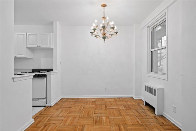 1299 Palmer Ave Unit 218, Larchmont, NY 10538 - kitchen with radiator, white gas range oven, a chandelier, white cabinets, and baseboards