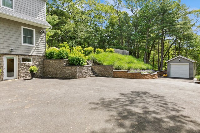 79 Oakside Rd, Smithtown, NY 11787 - view of patio with an outdoor structure, a garage, driveway, and view of wooded area