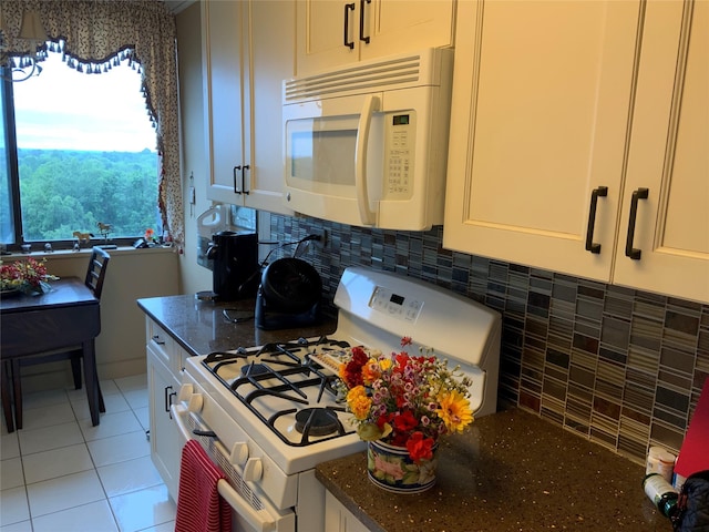 26910 Grand Central Pkwy Unit 8N, Floral Park, NY 11005 - kitchen featuring white appliances, dark stone counters, decorative backsplash, light tile patterned flooring, and white cabinetry