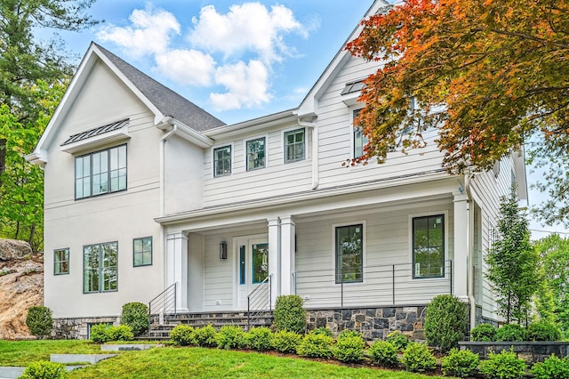 2 Lavender Ln, Rye, NY 10580 - view of front of house featuring a porch, a front lawn, stucco siding, and stone siding