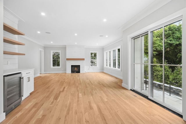 2 Lavender Ln, Rye, NY 10580 - unfurnished living room featuring wine cooler, crown molding, baseboards, plenty of natural light, and light wood-style flooring