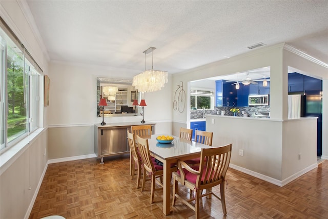 304 Heritage Hls Unit C, Somers, NY 10589 - dining space with healthy amount of natural light, a chandelier, crown molding, a textured ceiling, and ceiling fan