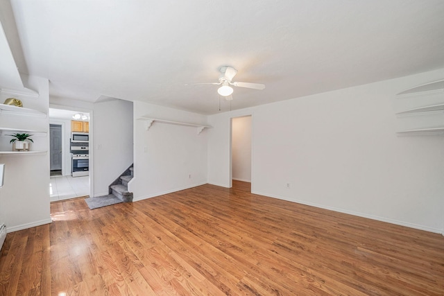 218 Beaver Dr, Mastic Beach, NY 11951 - unfurnished living room with stairs, a ceiling fan, light wood-style flooring, and baseboards